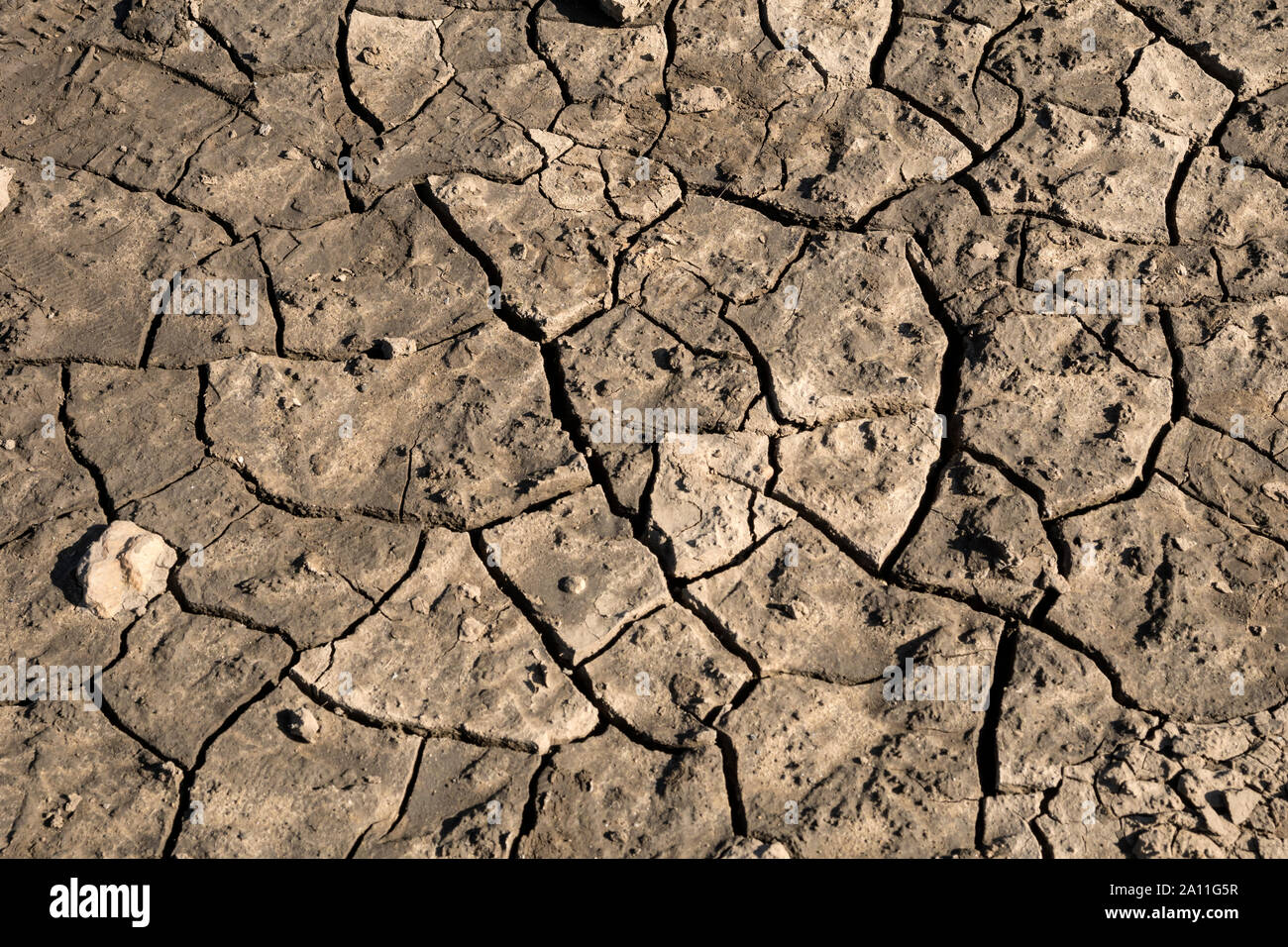 Dried and cracked mud on a dry reservoir floor Stock Photo