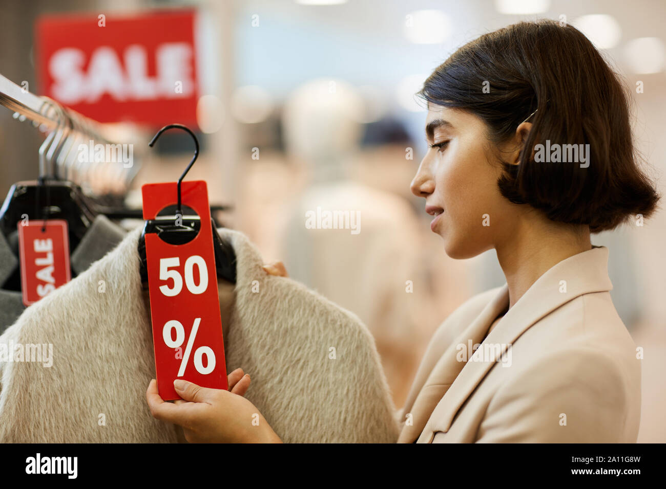 Side view portrait of beautiful young woman choosing winter clothes on