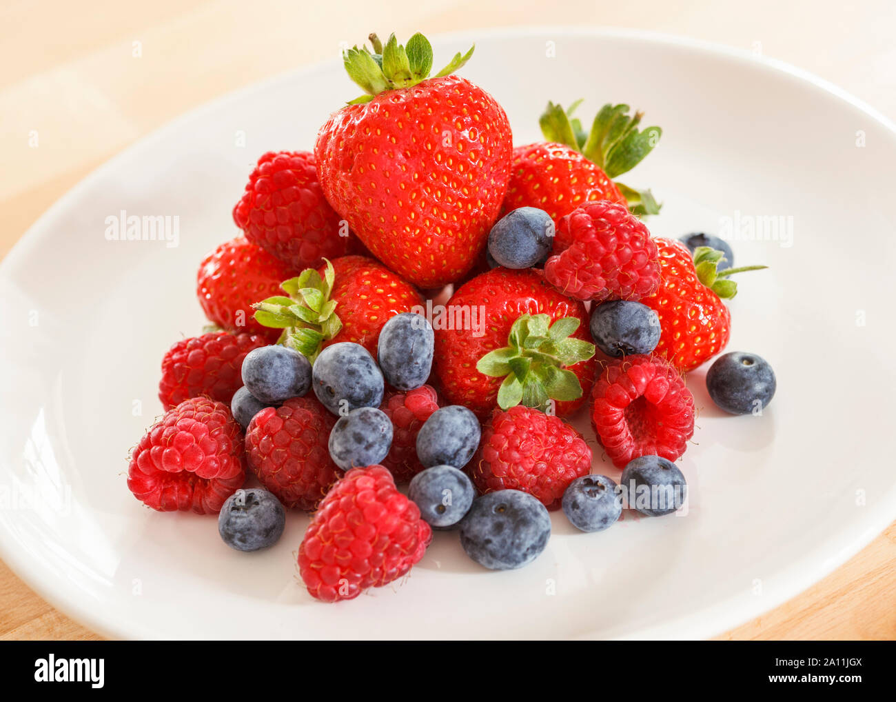 Pile of mixed berries on a white plate Stock Photo