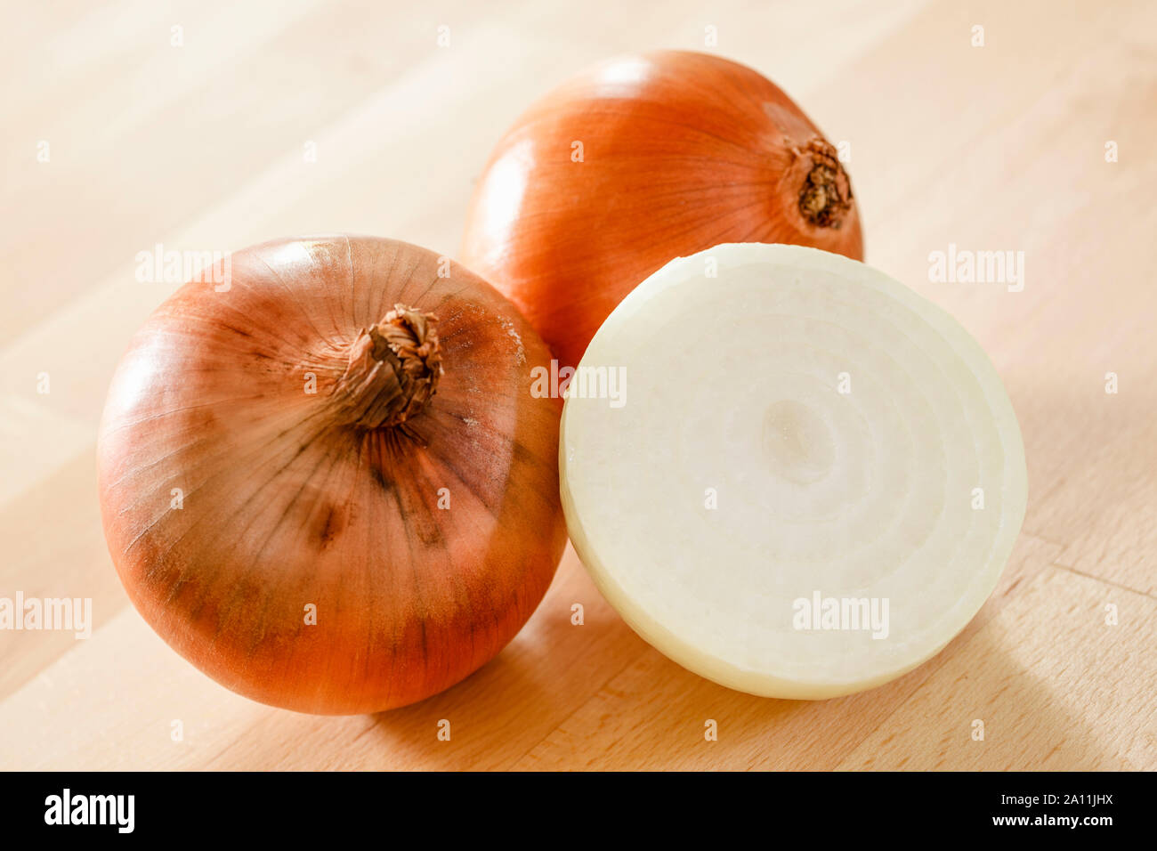 Onions, whole and half on a wooden surface Stock Photo