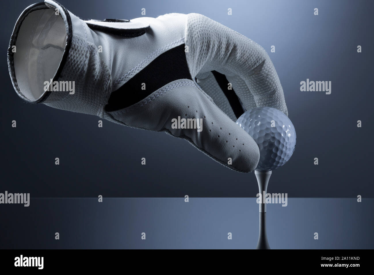 Close up of empty golf glove putting a golf ball on tee. Stock Photo