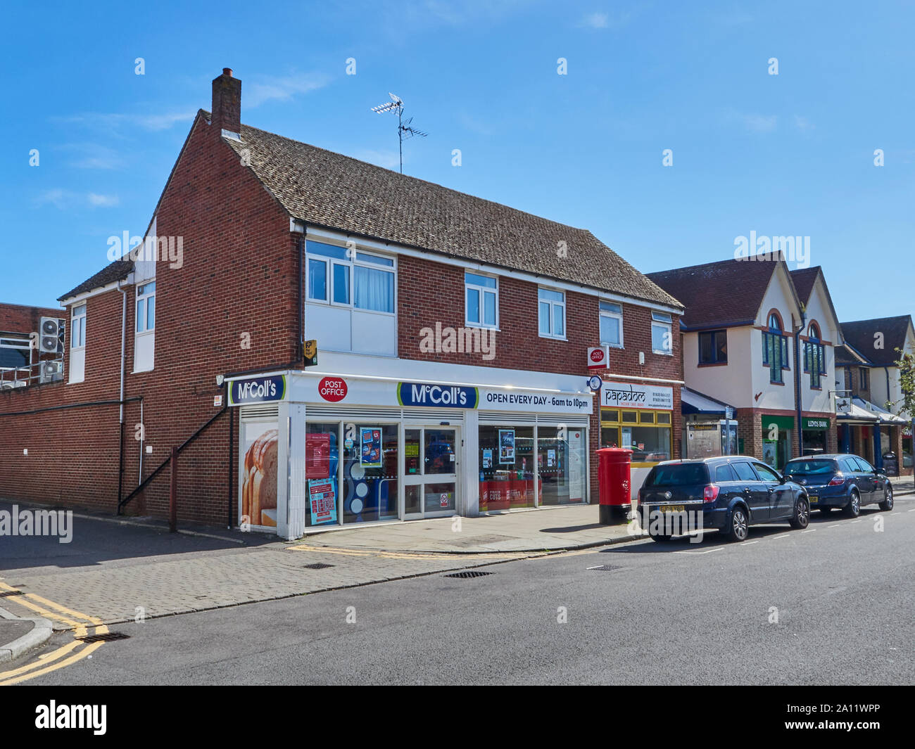 Outside view of McColls newsagents and other shops in the Broadway high street in Thatcham with cars parked outside, Thatcham, Berkshire, UK Stock Photo