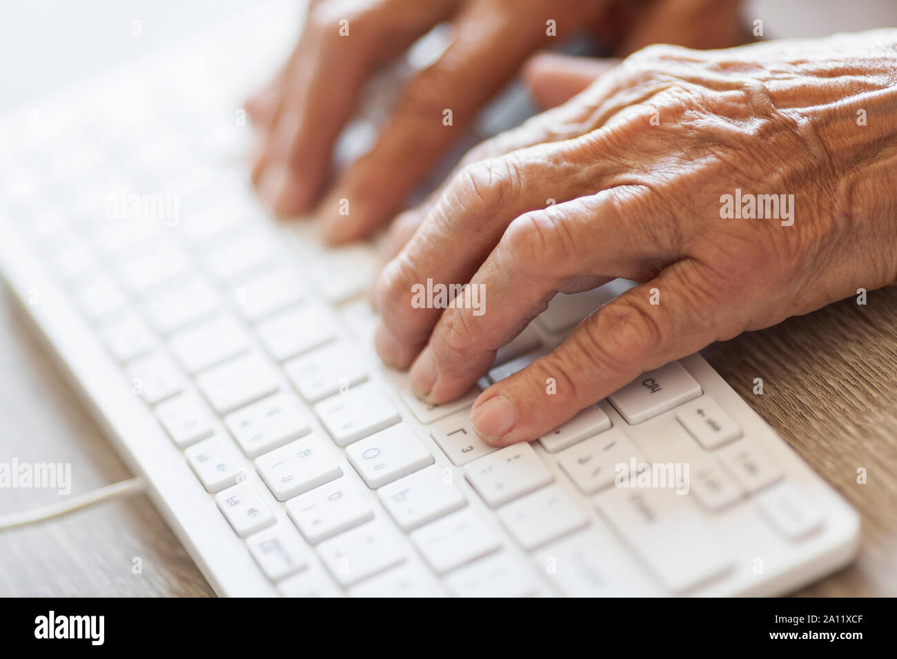 Elderly woman typing on a PC keyboard Stock Photo