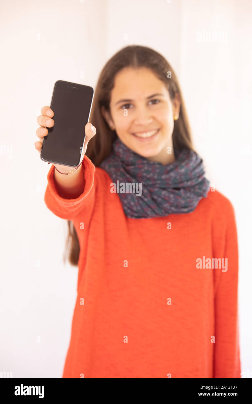 Chica adolescente feliz mostrando una maqueta de teléfono inteligente Stock Photo