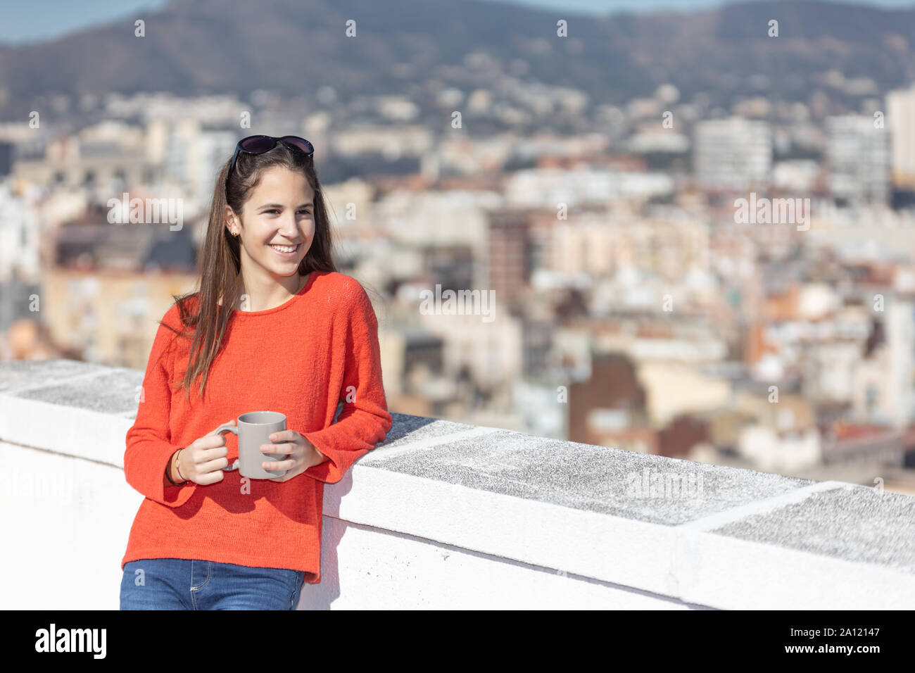 Chica adolescente feliz tomando un café en la azotea Stock Photo