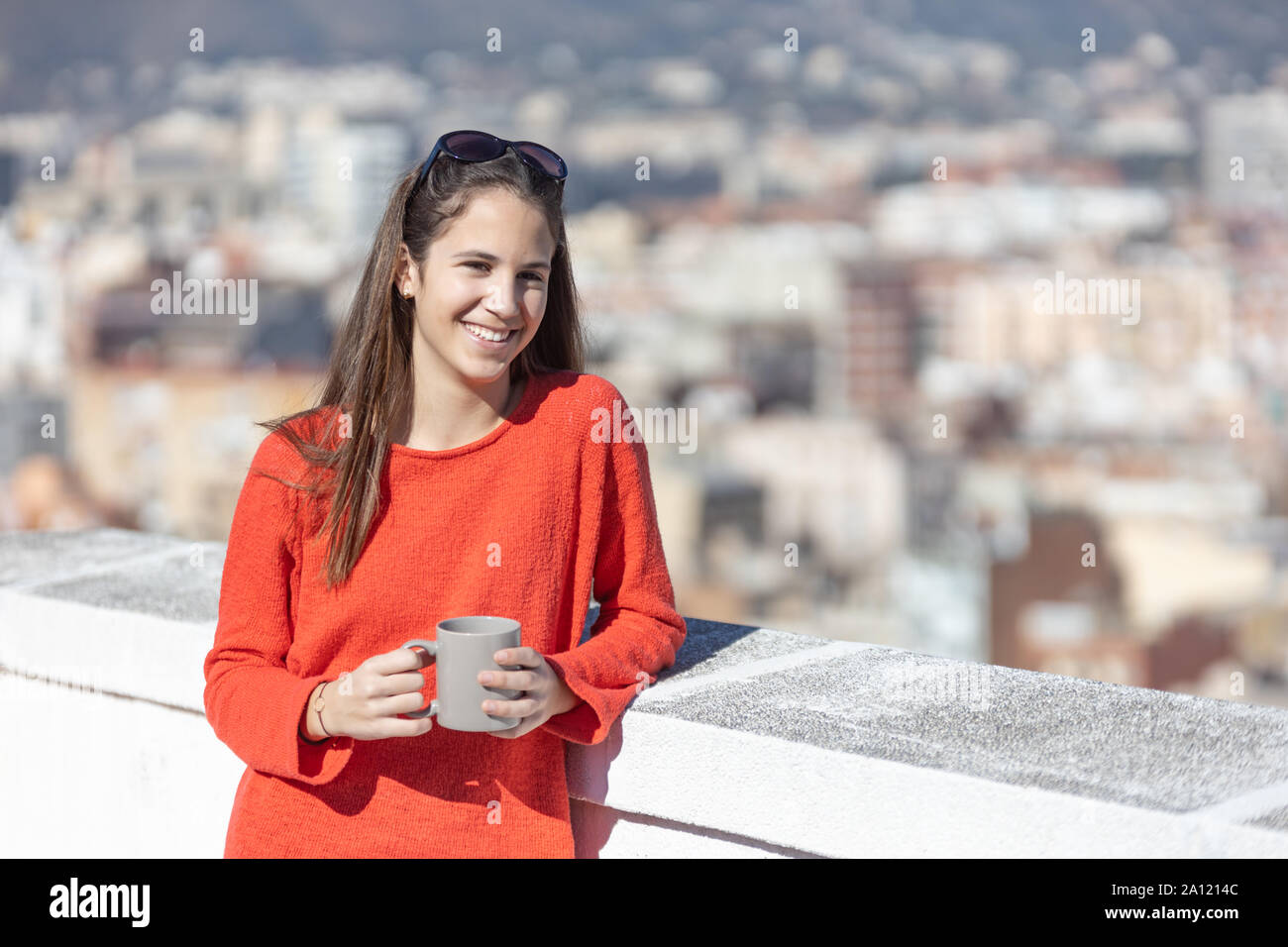 Chica adolescente tomando un café mirando a la cámara en la azotea Stock Photo
