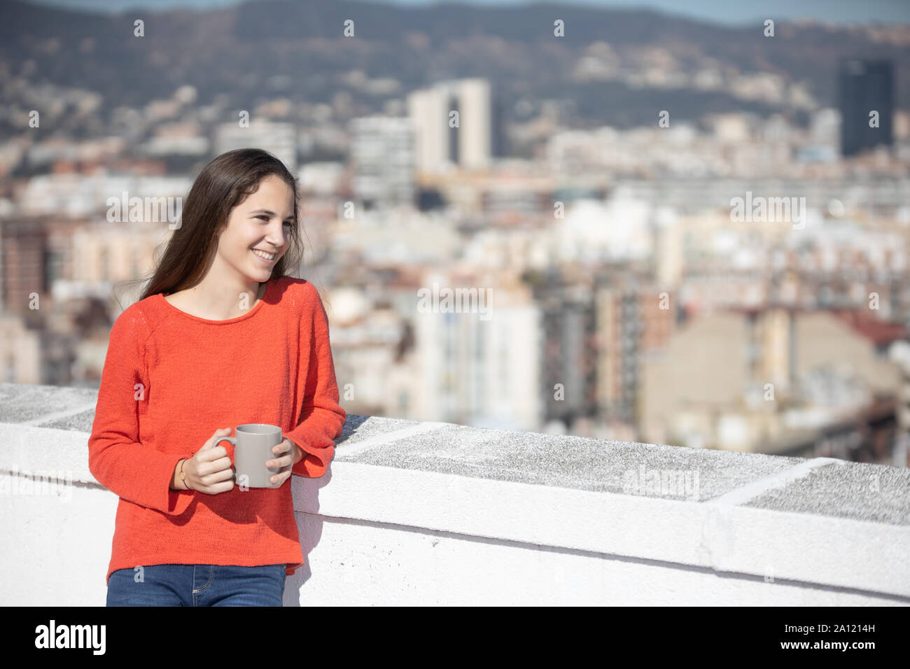 Chica adolescente feliz tomando un café en la azotea Stock Photo