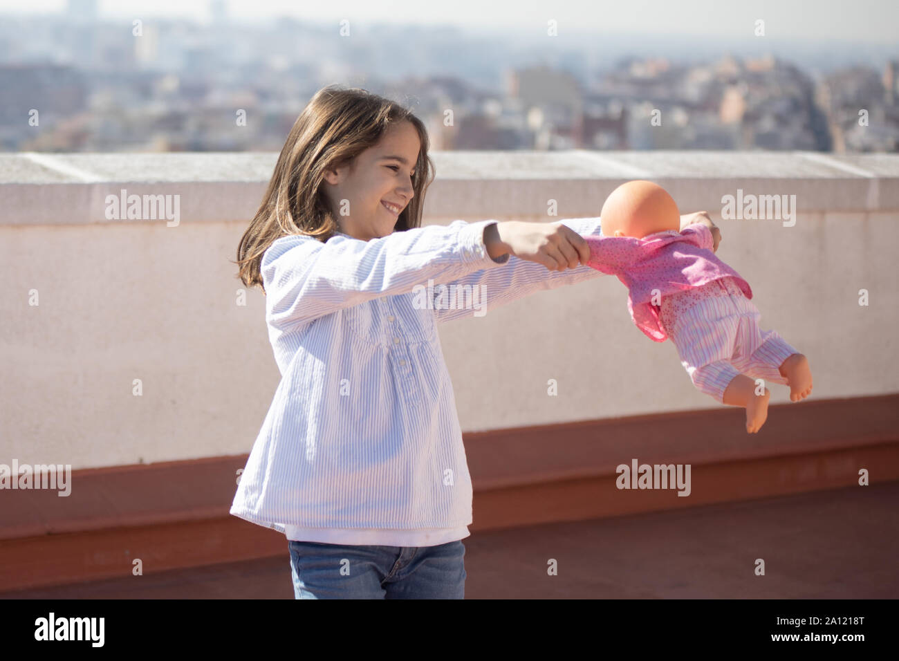 Niña de pie jugando con una muñeca en la azotea Stock Photo