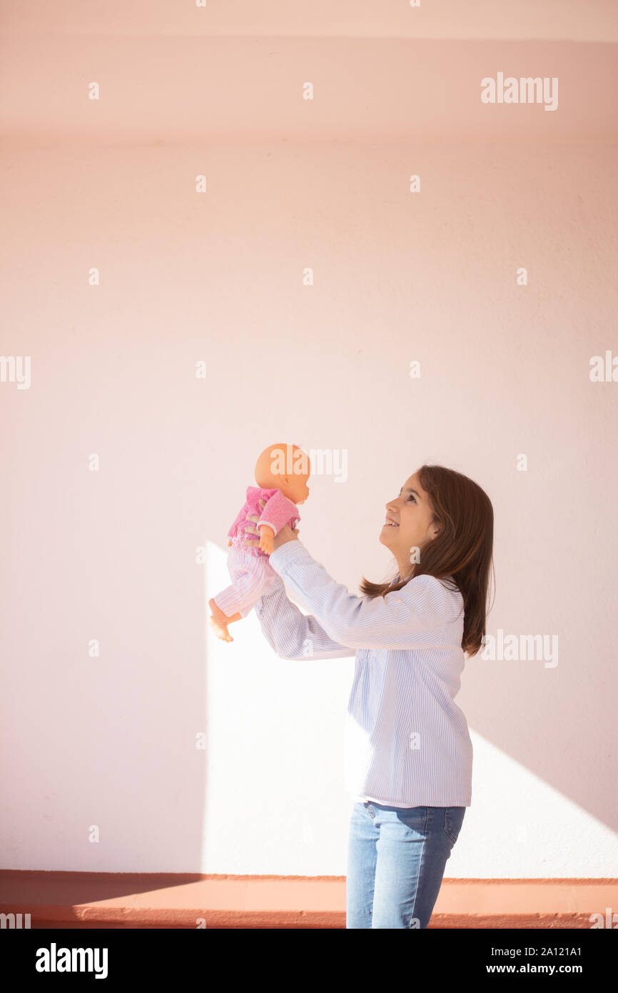 Niña de pie jugando con una muñeca en la azotea Stock Photo