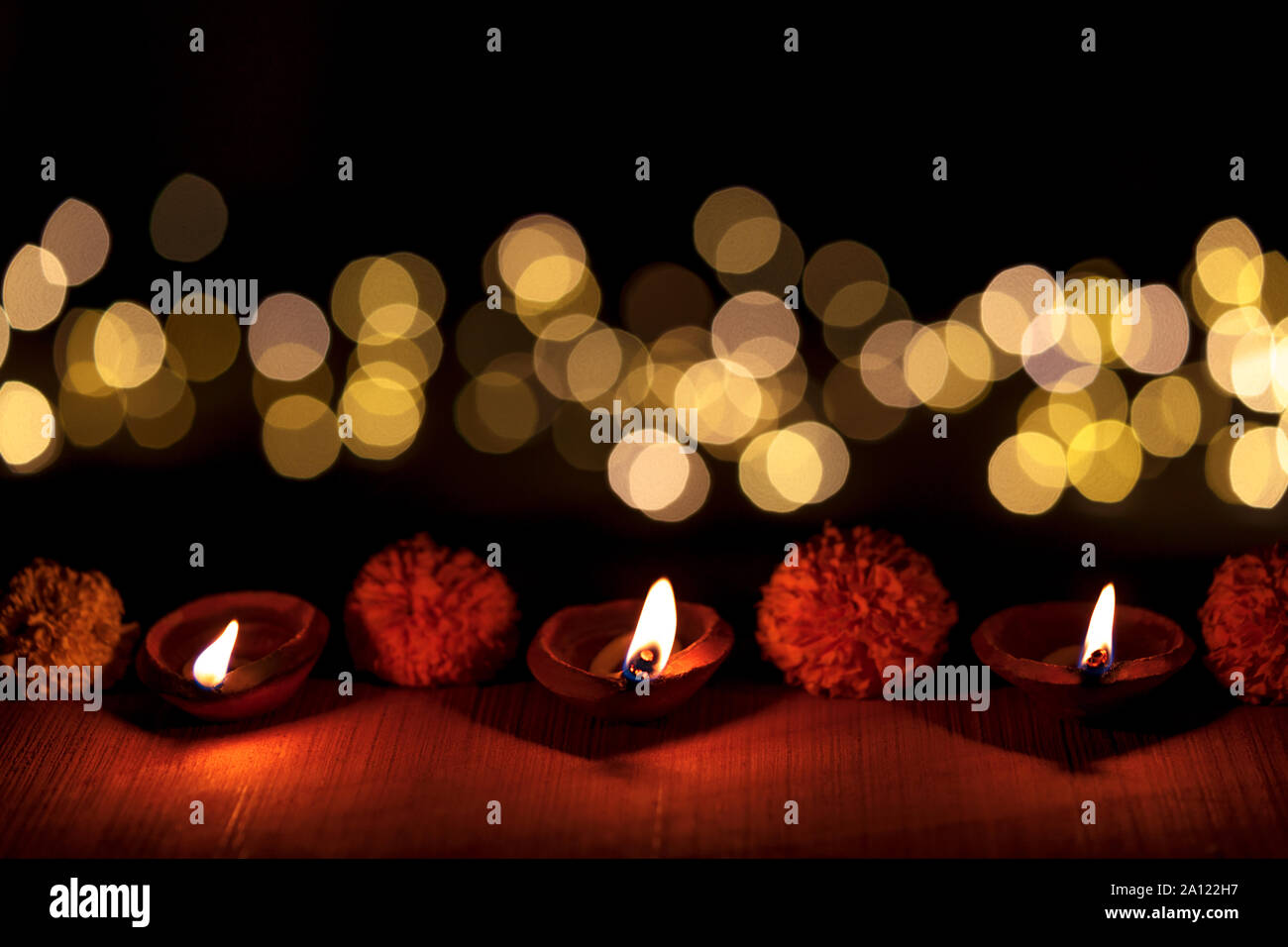 Dark moody diya or terracotta lamp lit in a row during Diwali Indian Hindu Festival with bokeh light isoltaed on black background. Stock Photo