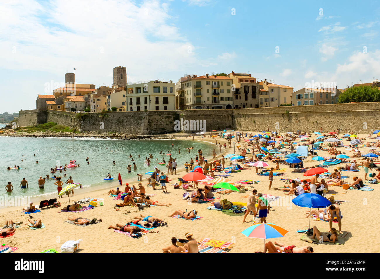 ANTIBES, FRANCE - AUGUST 07, 2019: Sandy beach with people and umbrellas and the Fort carré Chateau Grimaldi at Old Town Vieil Antibes Cote d'azur Fre Stock Photo