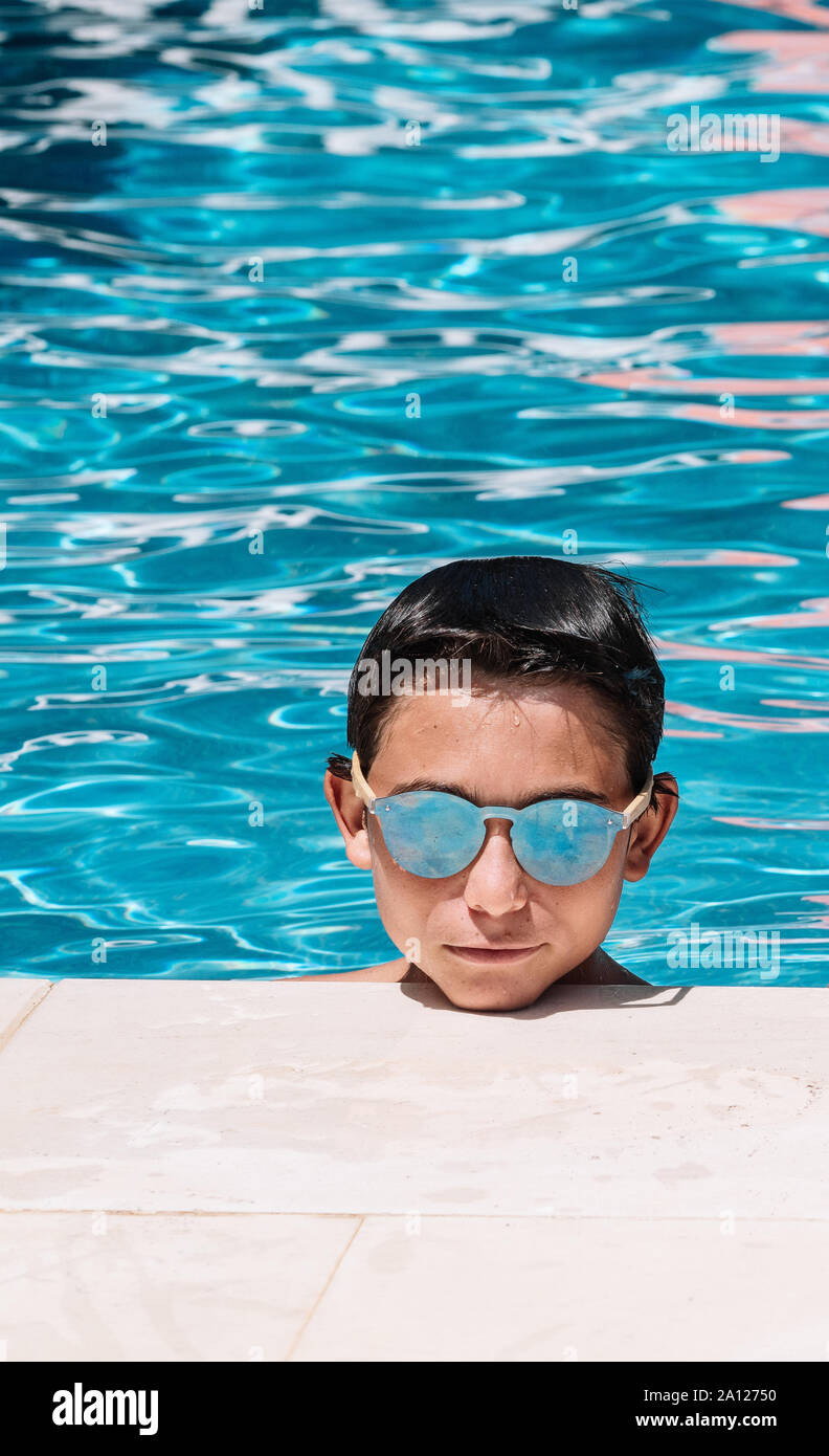 Pre-teens pose with sunglasses by the edge of the pool Stock Photo