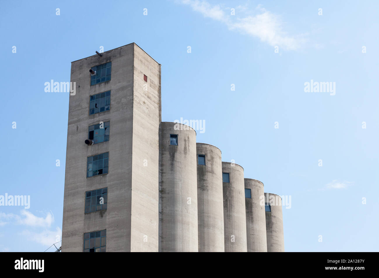 High Concrete Wheat Silo, old and abandoned, in an agricultural industry of Serbia, in Europe, with a blue sky in background, used to store grain  Pic Stock Photo