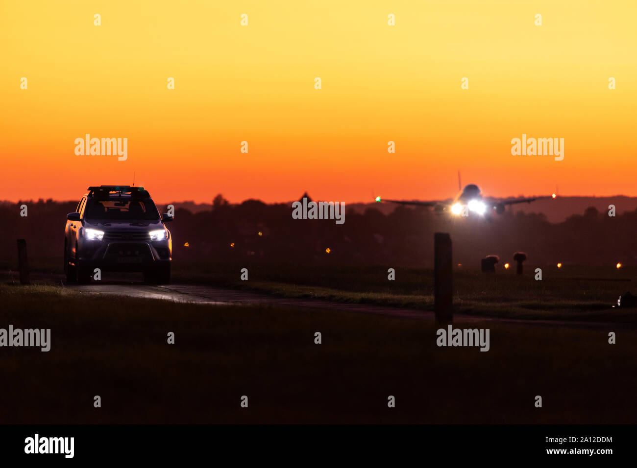 Airport operations vehicle driving along the perimeter road as an aircraft lands, London Luton Airport, September 19th 2019, Luton, Bedfordshire, UK Stock Photo