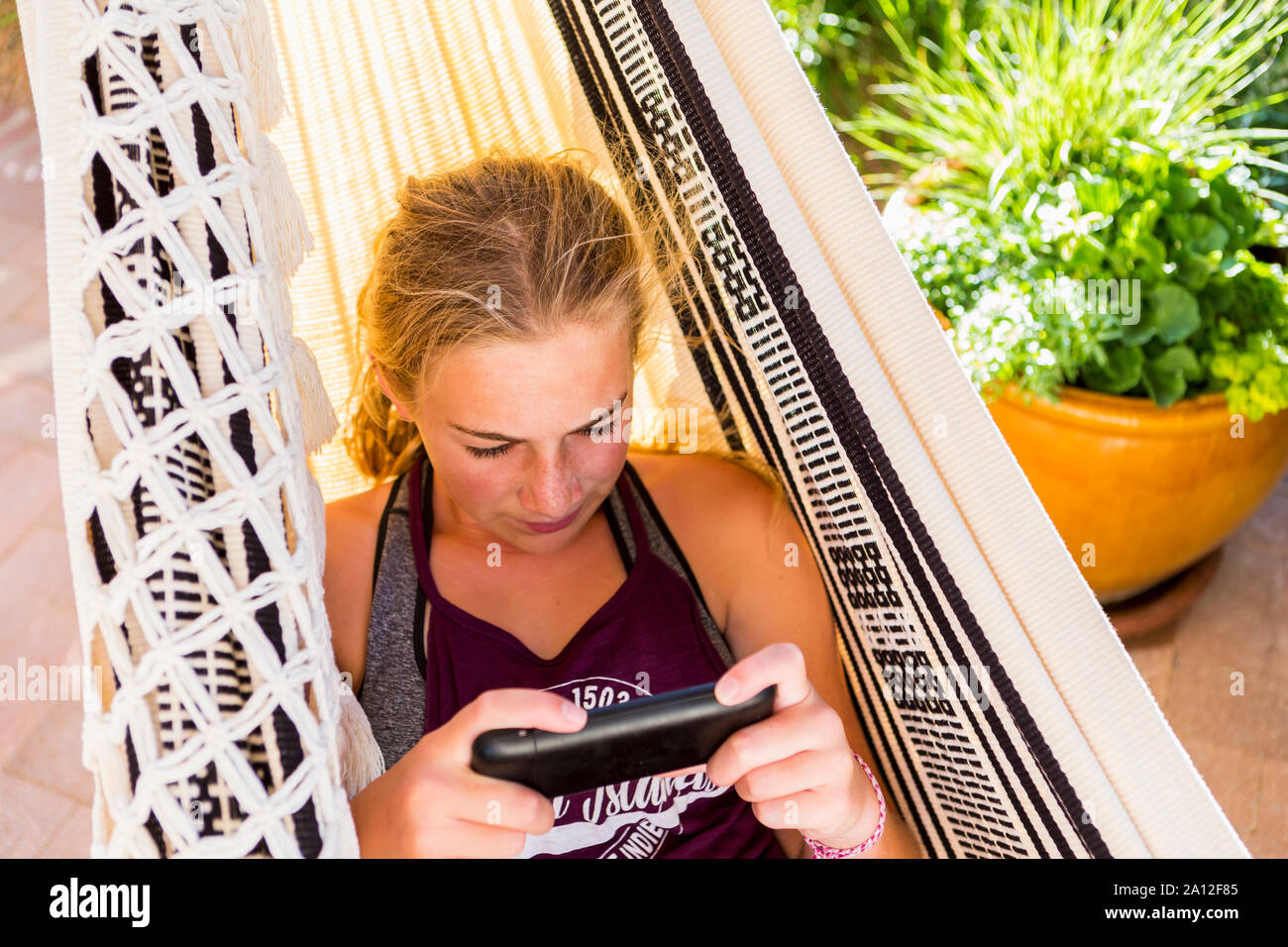 13 year old girl in hammock looking at smart phone Stock Photo