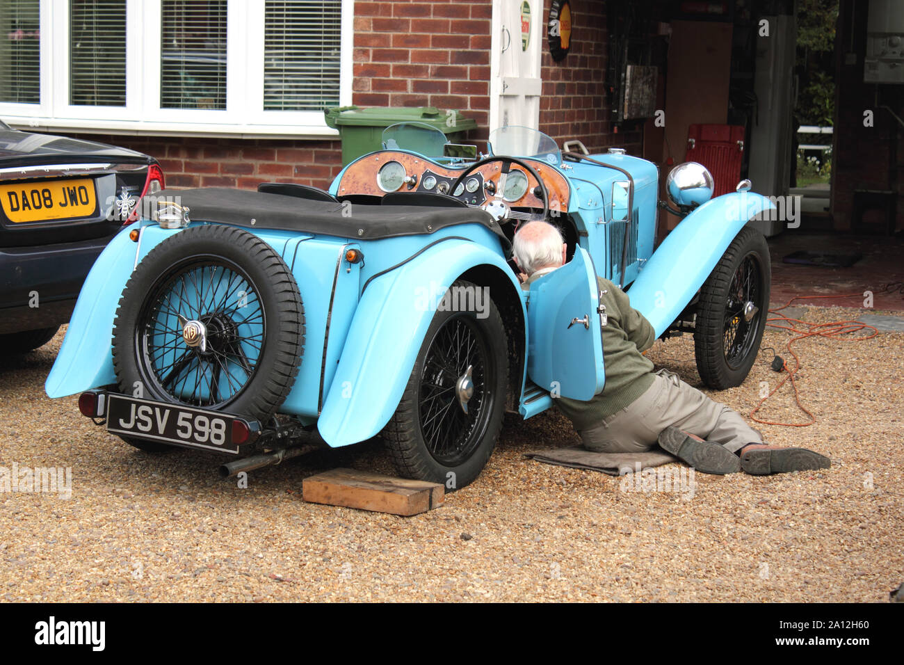 View of elderly man working on blue vintage Morgan car from the 1930s Stock Photo