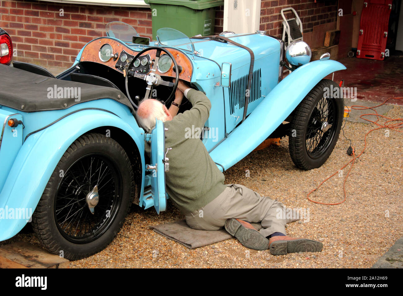 View of elderly man working on blue vintage Morgan car from the 1930s Stock Photo