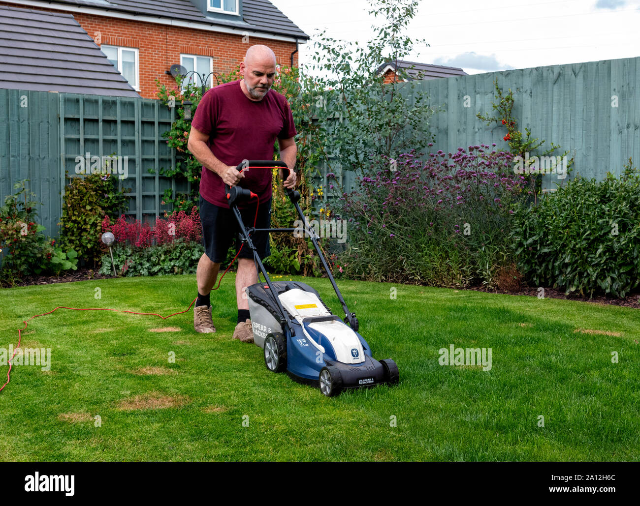 Man mowing his lawn with a Spear and Jackson electric lawnmower