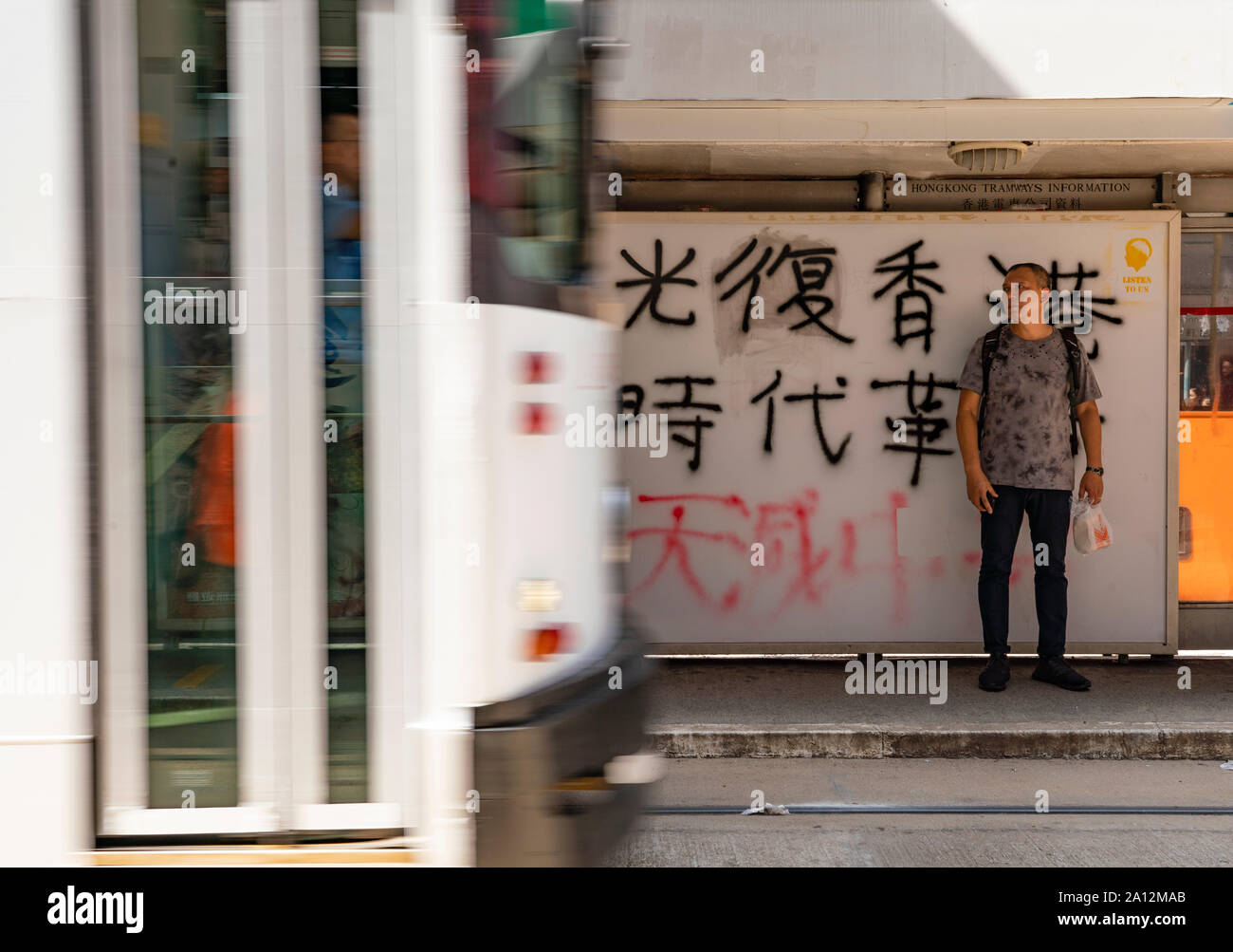 Vandalised tram stop in Hong Kong with slogans of the prodemocracy movement spray painted onto screen. Stock Photo