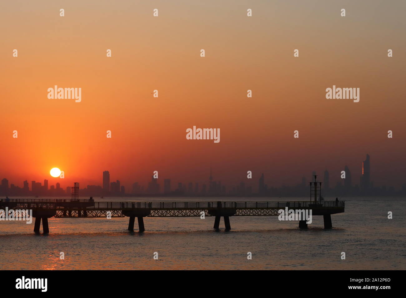 Pier and city skyline silhouetted against a spectacular setting sun Stock Photo