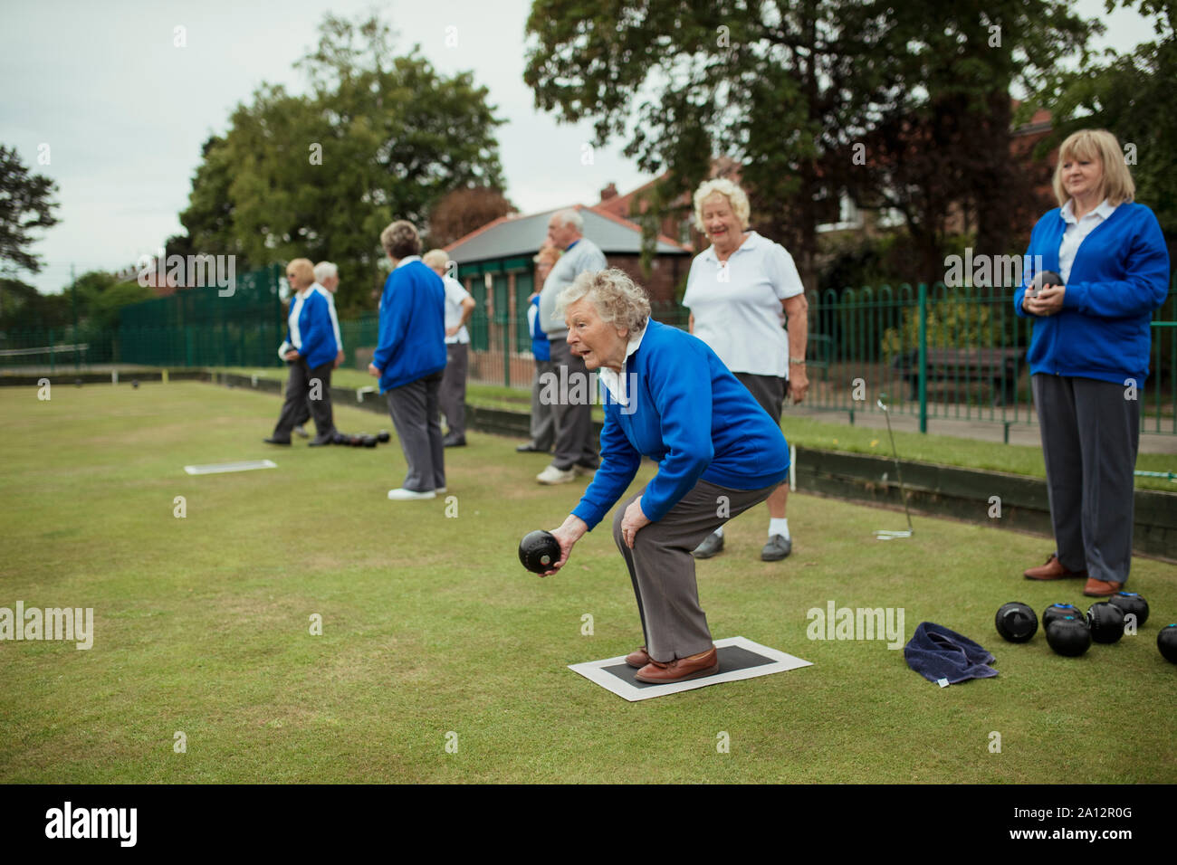 A side view shot of a senior woman playing lawn bowling with other seniors. Stock Photo