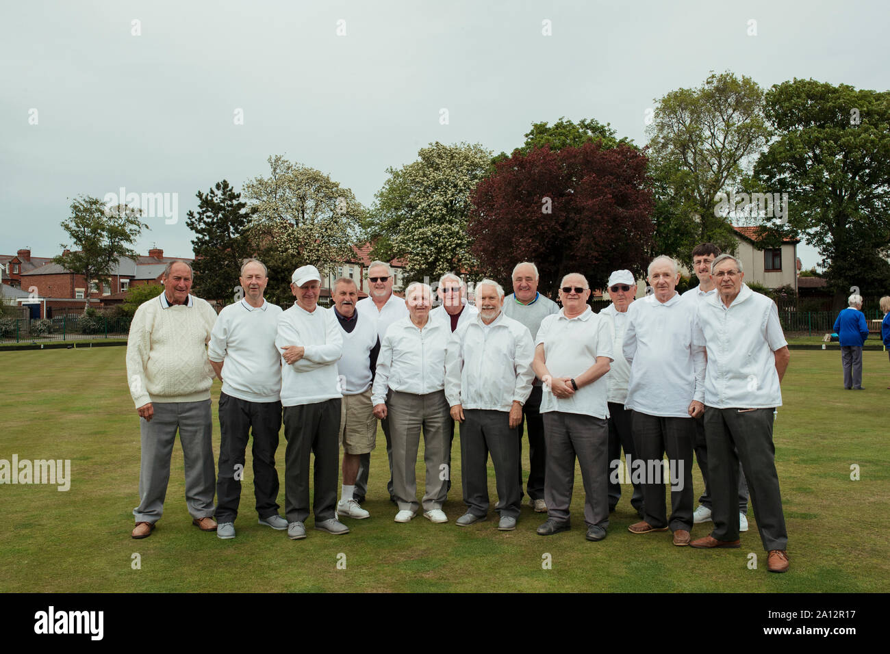 A front view shot of a community of senior men smiling at a bowling green. Stock Photo