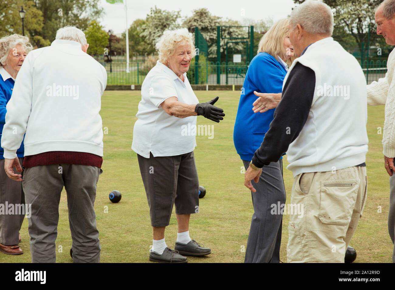 Senior adults shaking eachother's hands after a lawn bowling game, showing team spirit. Stock Photo