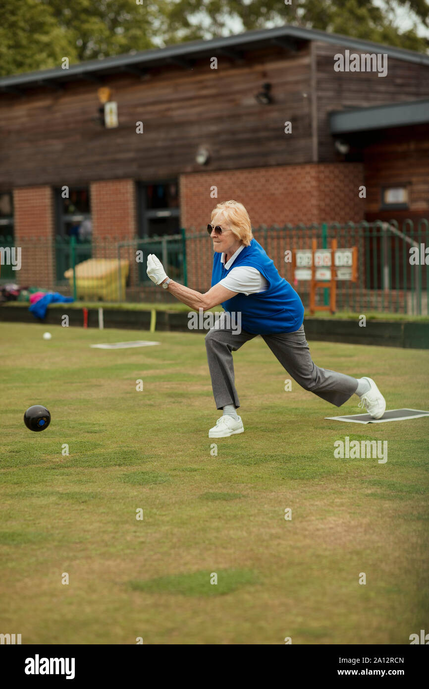 A side view shot of a senior woman taking her shot in a game of lawn bowling. Stock Photo