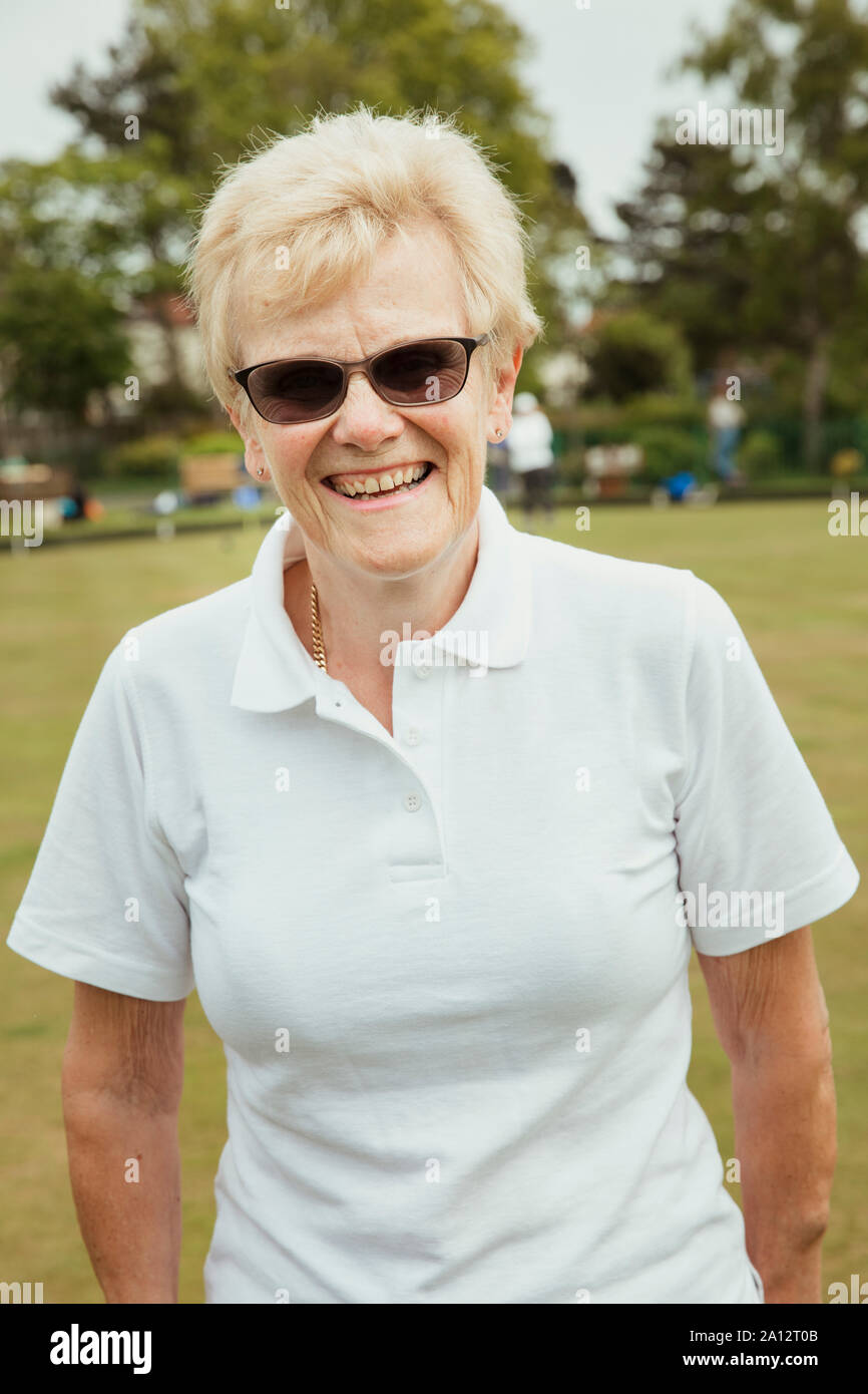 A portrait of a senior woman smiling at a bowling green. Stock Photo