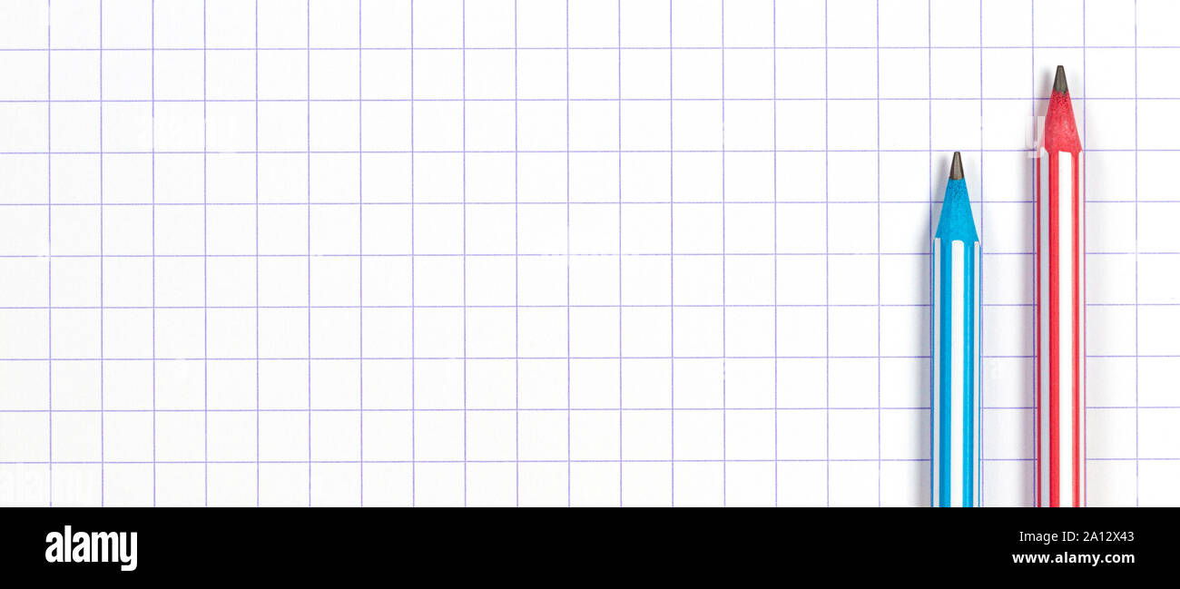 Two striped pencils on white squared paper notebook background. Top view Stock Photo