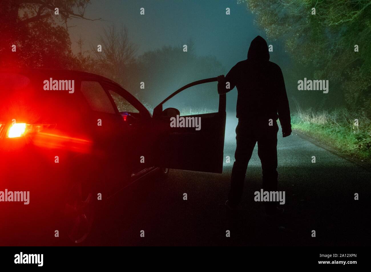 A Spooky Mysterious Hooded Figure Standing Next To A Car With