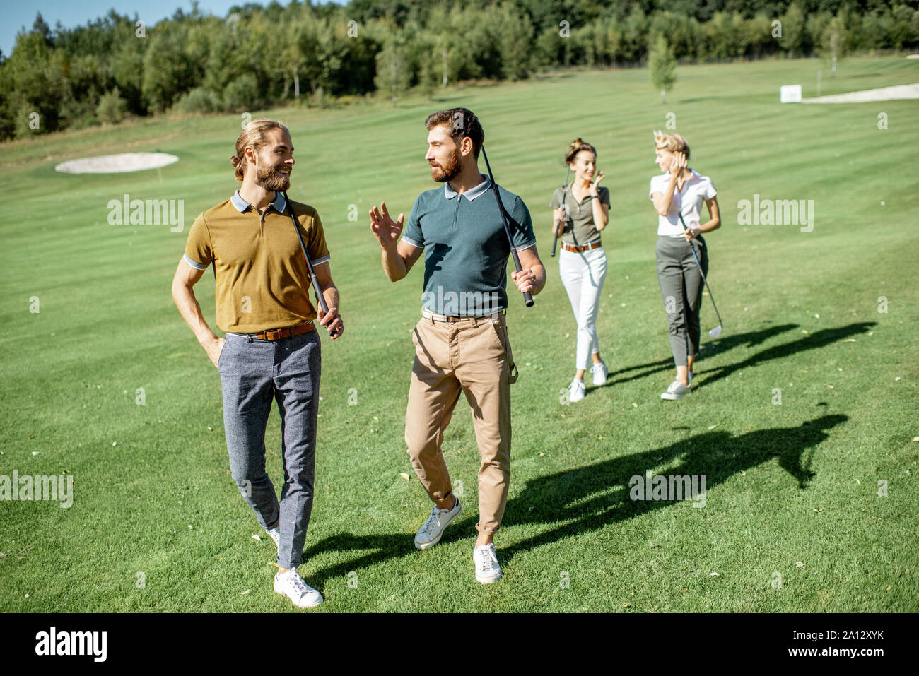 Group of friends talking and walking with putters during the golf play on  the beautiful course on a sunny day Stock Photo - Alamy