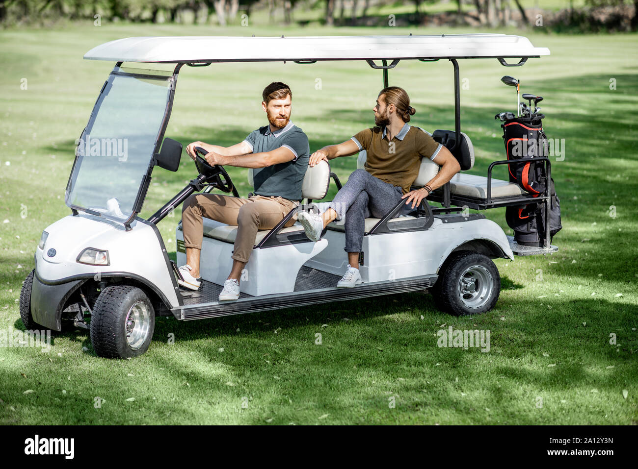 Two male best friends having fun while driving a golf car on the
