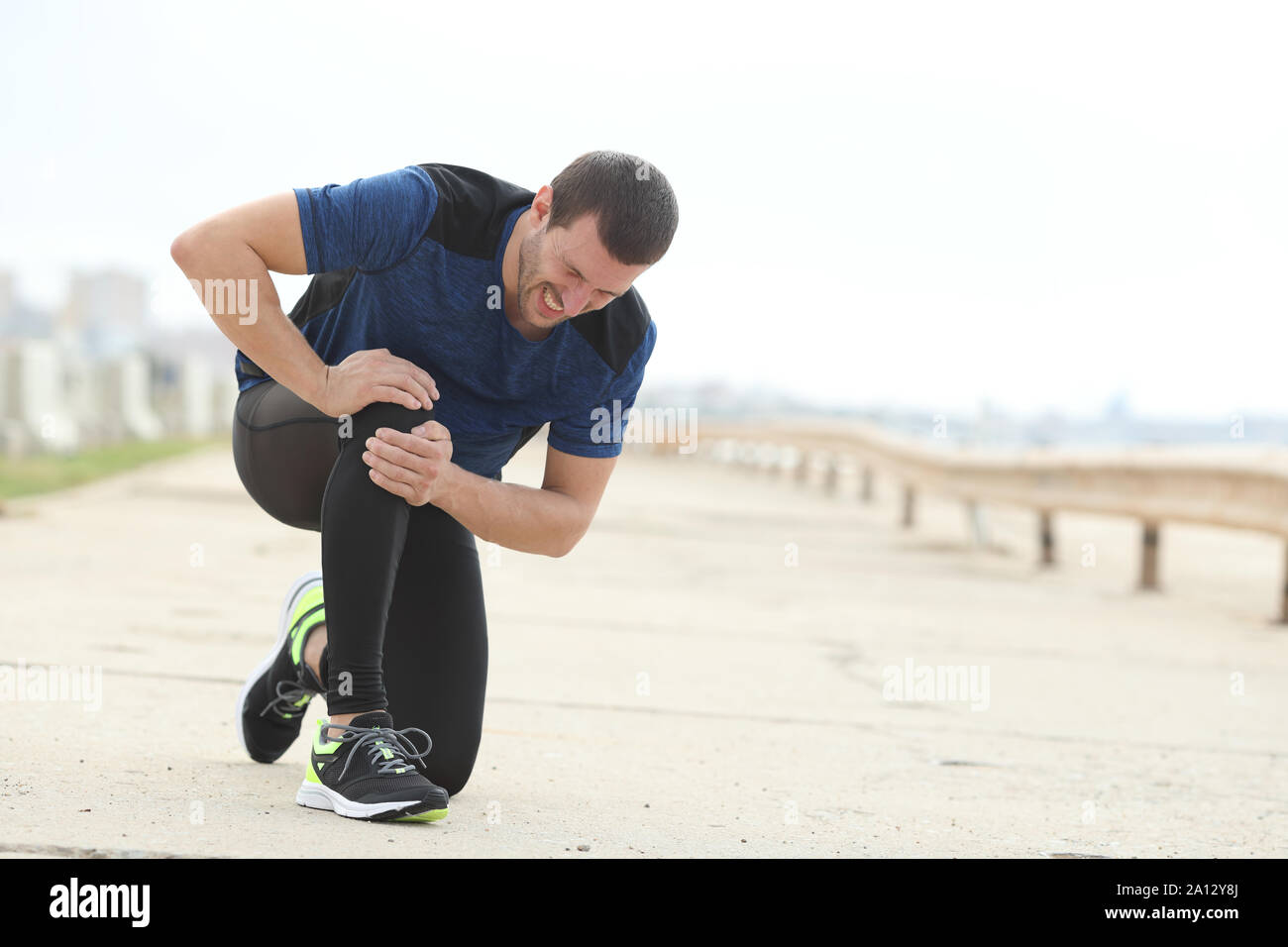 Painful jogger complaining suffering knee ache after sport on a concrete way Stock Photo Alamy