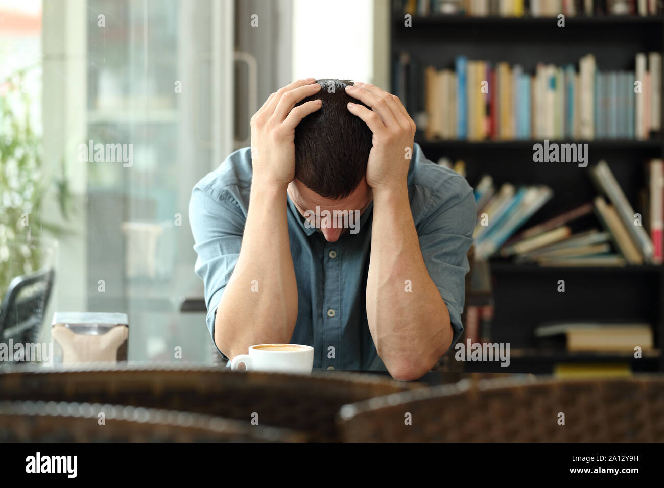 Front view portrait of a sad man complaining alone in a coffee shop Stock Photo