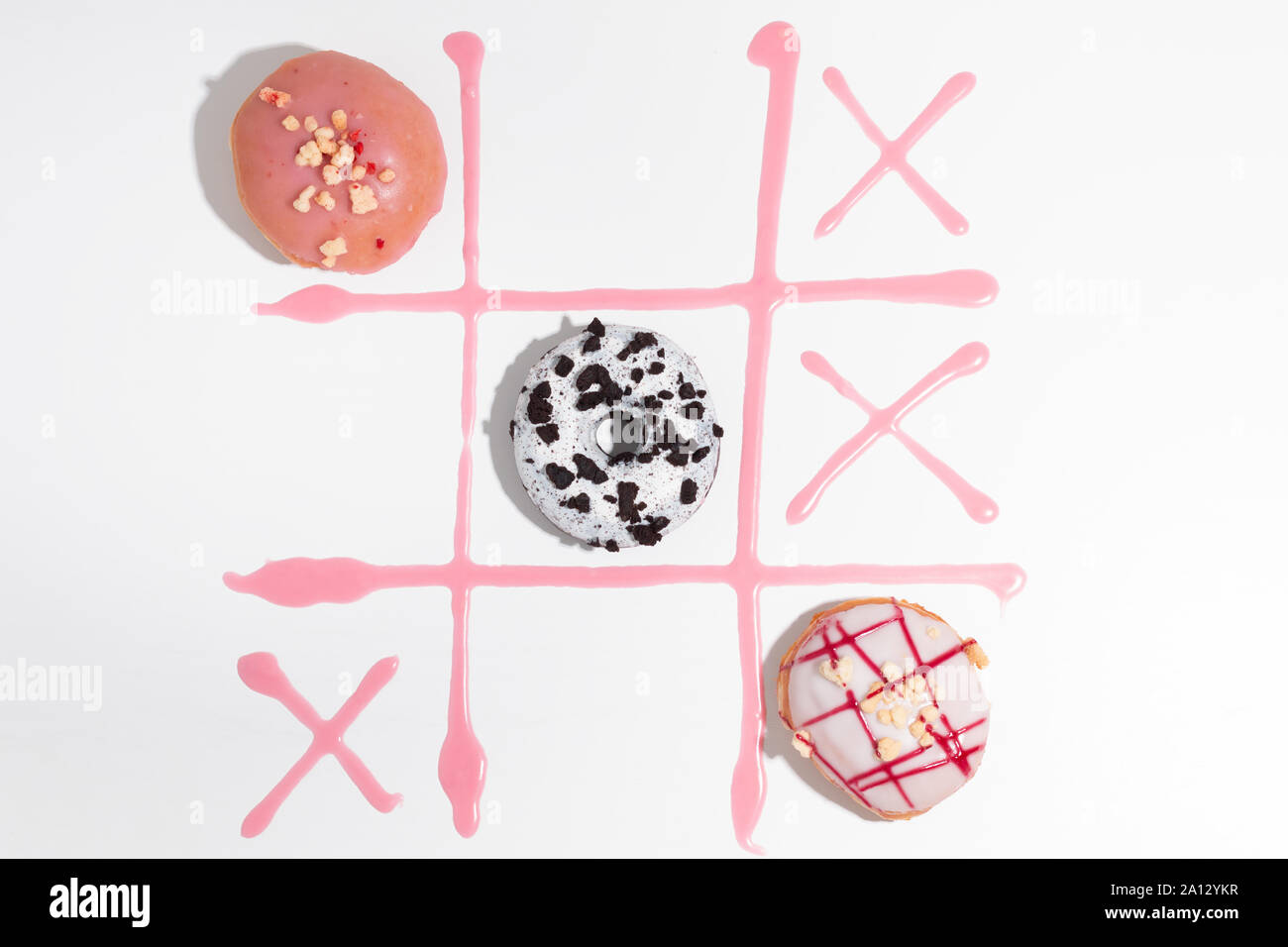 Delicious donuts and pink icing on a white background. Tic-tac-toe concept. Stock Photo