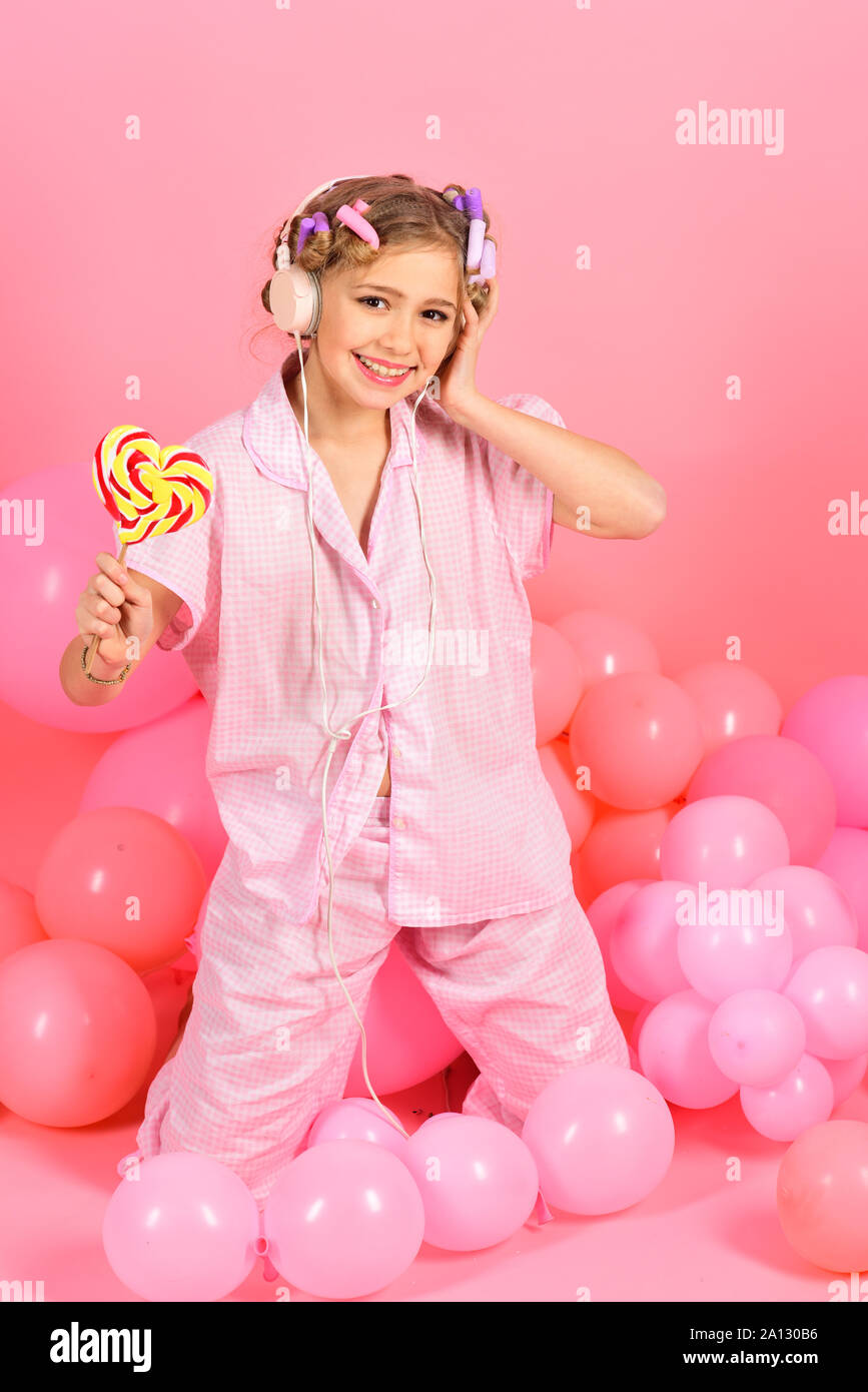 Happy little girl with lollipop in studio on pink background Stock Photo