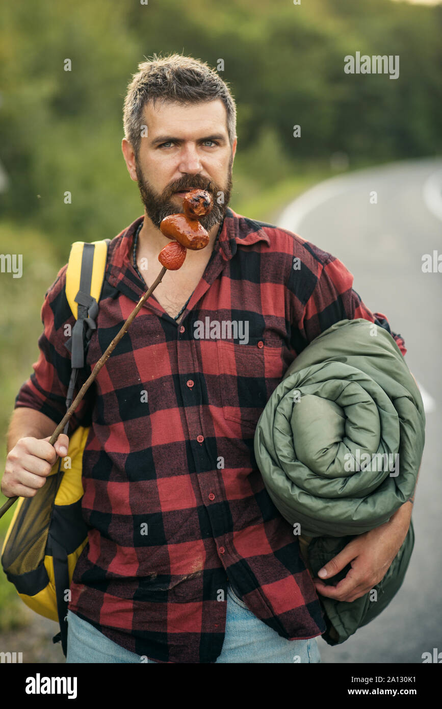 Hitchhiker on the way back to town. Bearded man with rucksack, sleeping