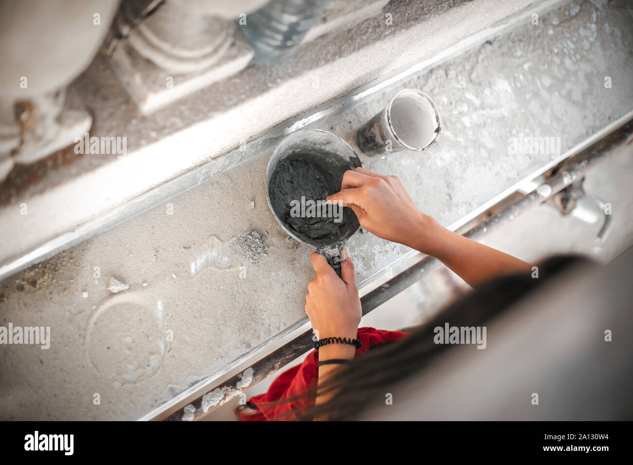 Female worker plastering old building wall using cement plaster mix of