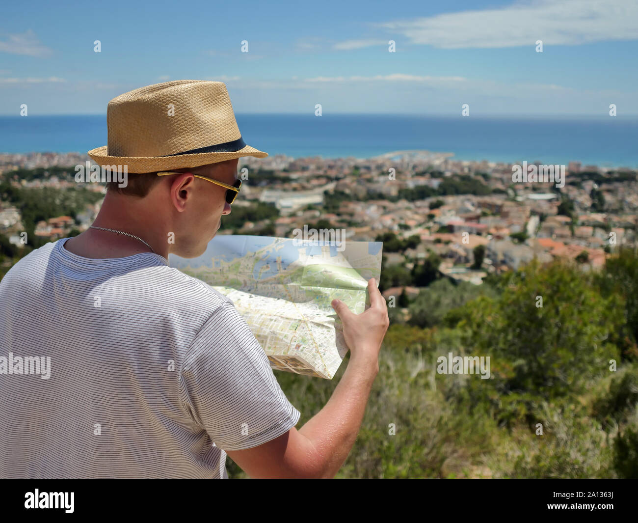 The guy a tourist is considering a map of the area, a city on the coast Stock Photo