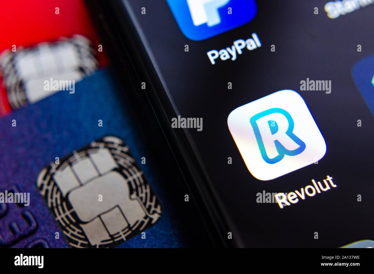 Revolut bank app on the smartphone screen, next to bank cards. Stock Photo