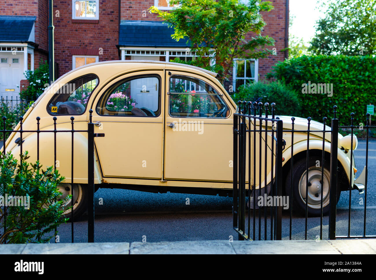 The classic car Citroën 2CV parked next to a picturesque house in England. Stock Photo