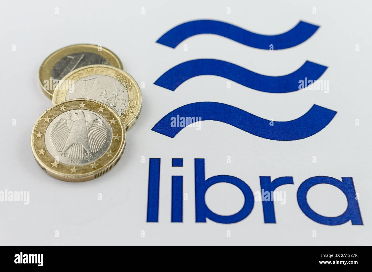 Facebook Libra cryptocurrency logos printed and the Euro coins next to them. Close up photo with shallow depth of field. Stock Photo
