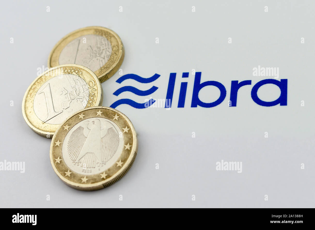 Facebook Libra cryptocurrency logos printed and the Euro coins next to them. Close up photo with shallow depth of field. Stock Photo