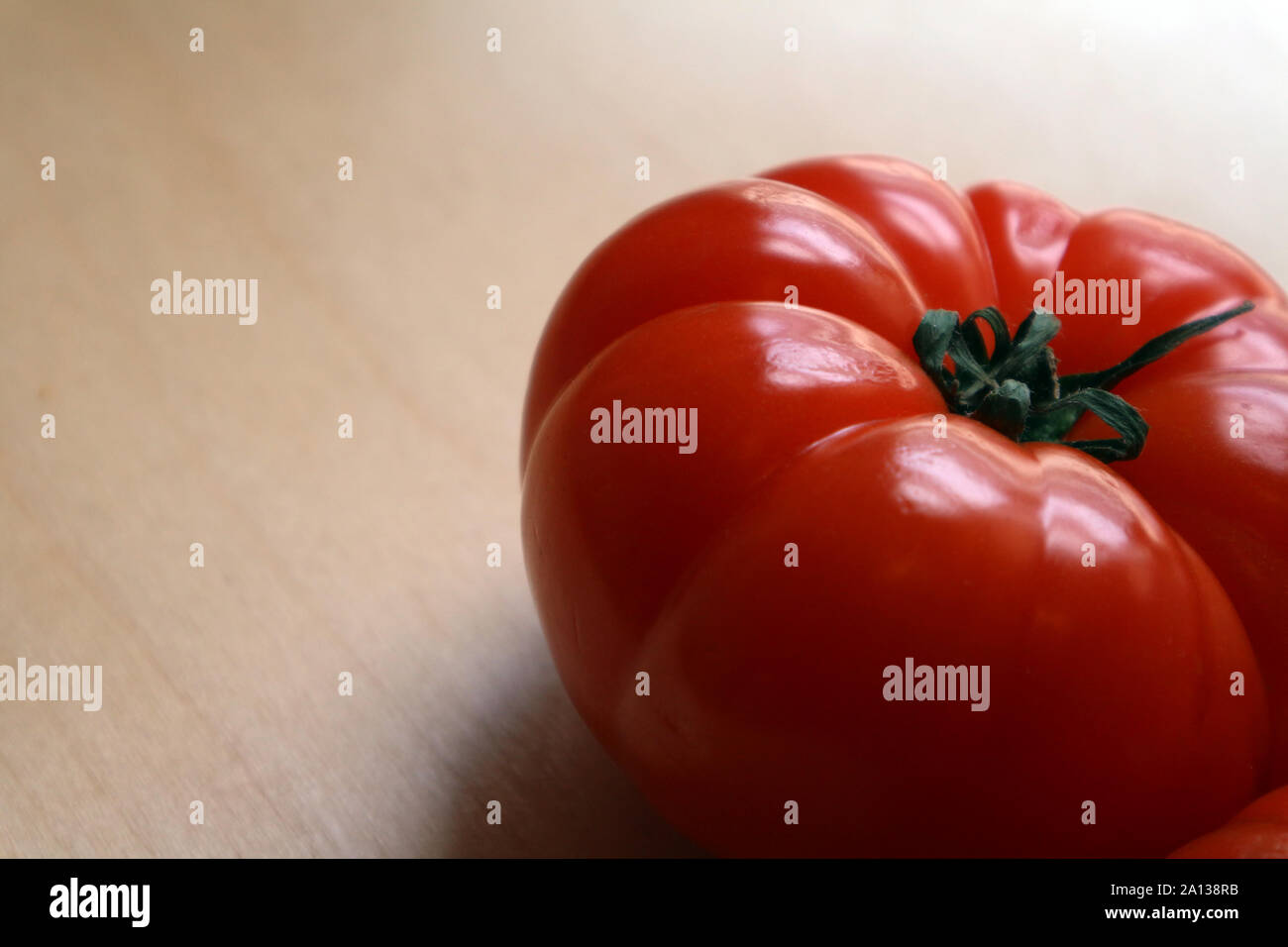 Single large ripe red whole tomatoes on chopping board Stock Photo