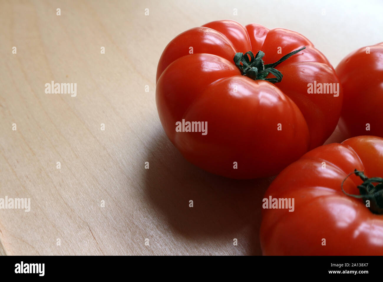 Large ripe red whole tomatoes on chopping board Stock Photo