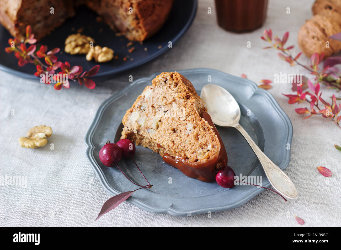 Apple pie with nuts, decorated with salted caramel and small red apples. Rustic style. Stock Photo