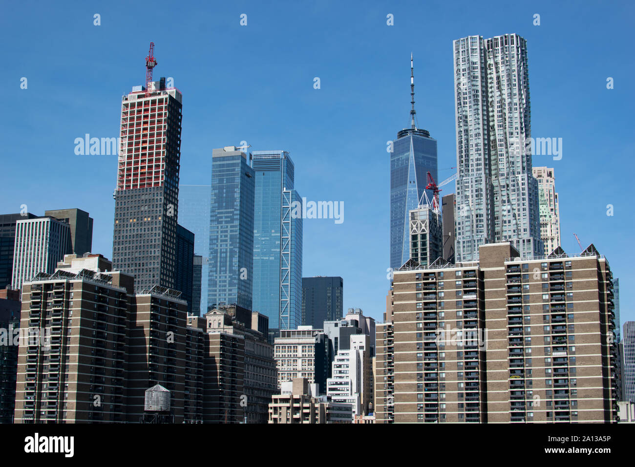 Blick auf die Skyline von Lower Manhattan mit One World Trade Center und Gehry Gebäude, NYC. Ein Wolkenkratzer befindet sich noch im Bau. Stock Photo