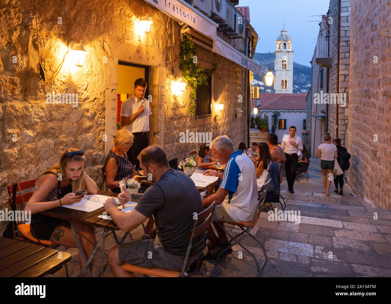 Dubrovnik holiday - tourists and locals eating at a restaurant outdoors in the evening, Dubrovnik old town, Dubrovnik Croatia Europe Stock Photo