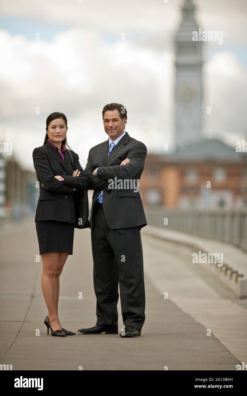 Portrait of two businesspeople standing in a city street with arms crossed. Stock Photo
